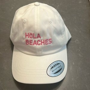 White hat with pink “hola beaches” script